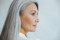 Middle aged Asian woman with beautiful straight hoary hair on light grey background Royalty Free Stock Photo