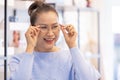 Middle aged asian woman choosing spectacles glasses in optician store. used correct or assist defective eyesight