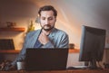 A middle-aged aspiring businessman with a beard thought about working in front of computers in the evening at home