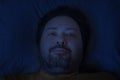 A middle-aged bearded man lies on a pillow late at night with a half smile on his face Royalty Free Stock Photo