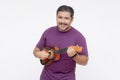 A middle aged bearded man playing the ukelele. Strumming a small guitar. Isolated on a white background Royalty Free Stock Photo