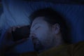 A middle-aged bearded man sleeps on a pillow late at night holding his hand with a phone to his head. Royalty Free Stock Photo