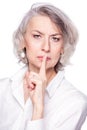 Middle aged beautiful woman putting her finger to her lips with a frown and stern look asking for quiet, isolated on Royalty Free Stock Photo