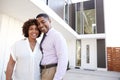 Middle aged African American couple stand outside admiring their modern home, back view
