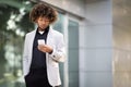 Middle aged black man entrepreneur in business suit standing outdoors near office building, sing cellphone, copy space Royalty Free Stock Photo