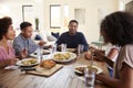 Middle aged African American man sitting at the table eating dinner with his wife and family, close up