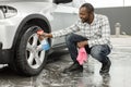 Middle aged black man with a sprayer bottle for polishing car in the car wash