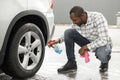 Middle aged black man with a sprayer bottle for polishing car in the car wash