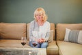 Middle-aged blond hair sad woman sitting on sofa with two glasses of red wine waiting for somebody man Royalty Free Stock Photo