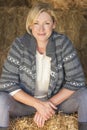 Middle Aged Blond Woman Sitting on Hay Bale Royalty Free Stock Photo