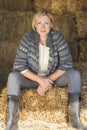 Middle Aged Blond Woman Sitting on Hay Bale Royalty Free Stock Photo