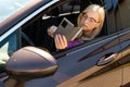 A middle aged blonde woman in glasses with a smartphone looks through an open car window Royalty Free Stock Photo