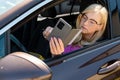 a middle aged blonde woman in glasses with a smartphone looks through an open car window Royalty Free Stock Photo