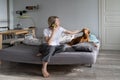 Middle-aged blonde woman talks on phone with friend and strokes favourite dog on bed Royalty Free Stock Photo