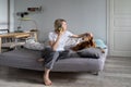 Middle-aged blonde woman talks on phone with friend and strokes favourite dog on bed Royalty Free Stock Photo