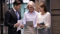 Mature boss and subordinates talking standing in office hallway