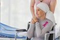 A middle-aged breast cancer woman with clothing around her head effected from chemo therapy sitting on wheel chair and hold hand