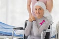 A middle-aged breast cancer woman with clothing around her head effected from chemo therapy sitting on wheel chair and hold hand