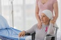 A middle-aged breast cancer woman with clothing around her head effected from chemo therapy sitting on wheel chair and hold hand