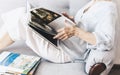 Middle-aged brunette woman on the gray sofa looking at album with paintings by artists Royalty Free Stock Photo