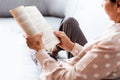 Middle-aged brunette woman on the gray sofa reading book, soft focus, stay at home concept, cozy background Royalty Free Stock Photo