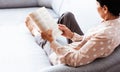 Middle-aged brunette woman on the gray sofa reading book, soft focus, stay at home concept, cozy background Royalty Free Stock Photo