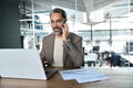 Middle aged business man ceo talking on cell phone working on laptop in office. Royalty Free Stock Photo