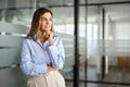 Middle aged business woman investor standing in office looking away.