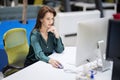 Mid aged businesswoman sitting in a modern office and using computer for work Royalty Free Stock Photo