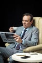 Middle aged businessman with coffee and newspaper sitting in armchair Royalty Free Stock Photo