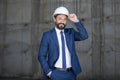 Middle aged businessman in hard hat and suit standing and smiling at work Royalty Free Stock Photo