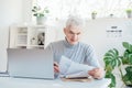 Middle aged businessman reading paper documents and using laptop while working at home office. Confident, experienced Royalty Free Stock Photo