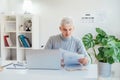 Middle aged businessman reading paper documents and using laptop while working at home office. Confident, experienced Royalty Free Stock Photo