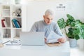 Middle aged businessman reading paper documents and using laptop while working at home office. Confident, experienced Royalty Free Stock Photo