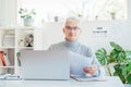 Middle aged businessman reading paper documents and using laptop while working at home office. Confident, experienced Royalty Free Stock Photo