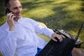 Middle Aged Businessman Sits On Grass Works On Laptop