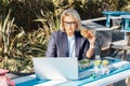 Middle-aged businesswoman having lunch at the park outdoor cafe, picnic area and working on laptop during her break Royalty Free Stock Photo