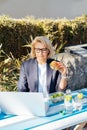 Middle-aged businesswoman having lunch at the park outdoor cafe, picnic area and working on laptop during her break Royalty Free Stock Photo