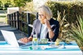 Middle-aged businesswoman having lunch at the park outdoor cafe, picnic area and working on laptop during her break Royalty Free Stock Photo