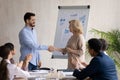 Middle aged businesswoman leader shaking successful employee hand