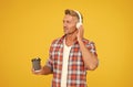 Middle-aged caucasian man listen to music in earphones holding hot coffee cup, break time Royalty Free Stock Photo