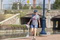 A middle aged caucasian woman wearing casual summer clothing is walking alone in Carroll Creek park