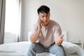 Middle aged chinese man sitting on bed, have phone conversation Royalty Free Stock Photo