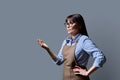 Middle-aged confident woman in apron looking in profile on gray background Royalty Free Stock Photo
