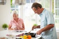 Middle Aged Couple Cooking Meal In Kitchen Together