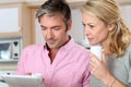 Middle-aged couple drinking coffee and using tablet in the kitchen Royalty Free Stock Photo