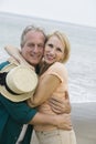 Middle-aged couple embracing on beach and looking at camera Royalty Free Stock Photo