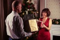 Middle-aged couple exchanging gifts while standing near Christmas tree . Royalty Free Stock Photo