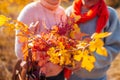 Middle-aged couple holding bouquet of autumn branches with yellow and red leaves. People hug outdoors