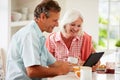 Middle Aged Couple Looking At Digital Tablet Over Breakfast Royalty Free Stock Photo